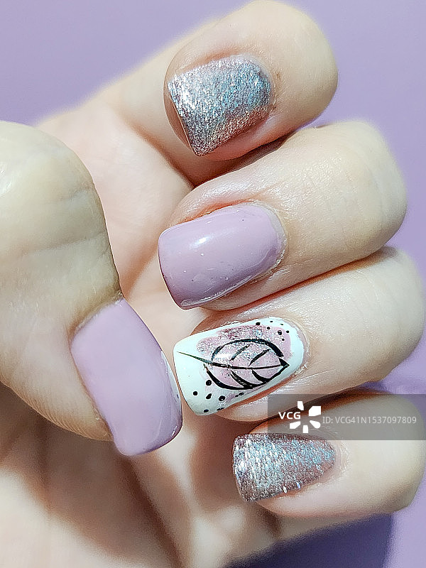 修剪过的手，浅粉色和银色指甲油与叶子设计图片素材