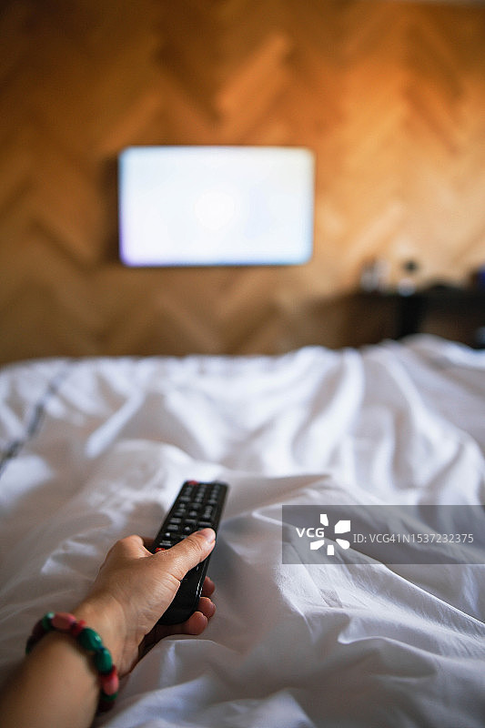 女子在卧室手持遥控器，电视屏幕空白图片素材