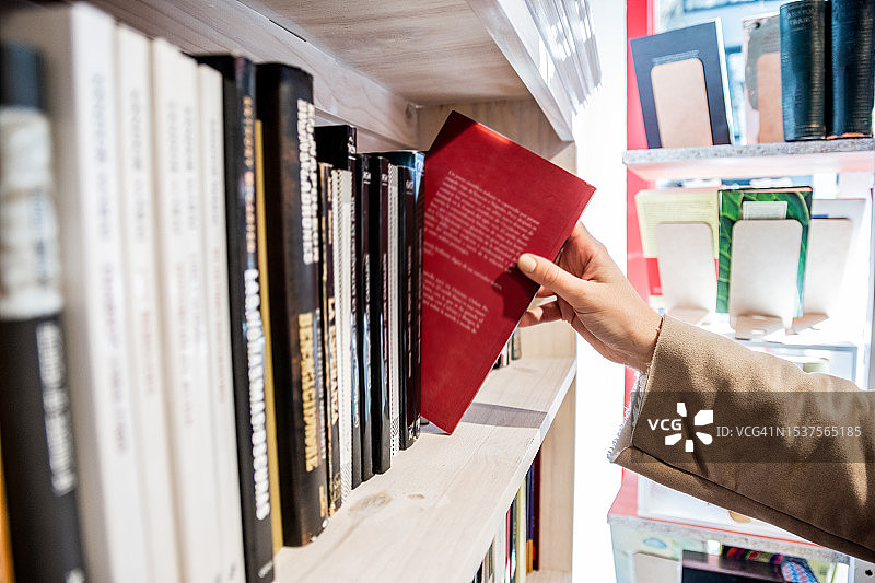 近距离拍摄：女人在图书馆书架上取书图片素材