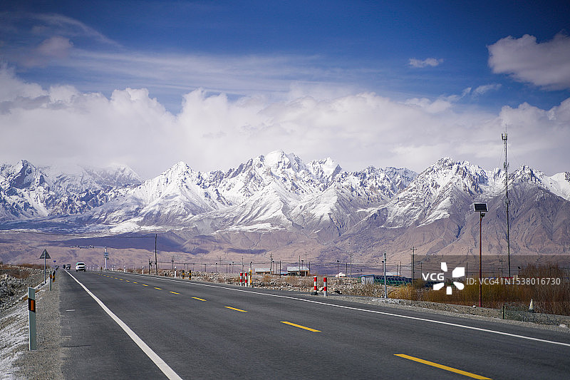 帕米尔高原雪山公路与空旷沥青路图片素材