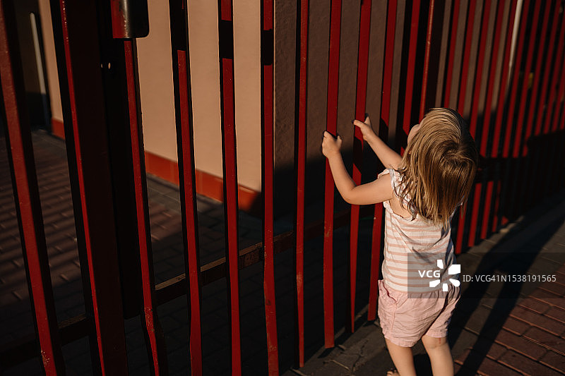 试图打开关闭的栅栏的小女孩图片素材