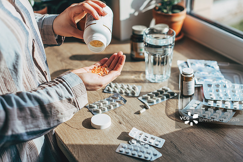 家庭急救箱顶部视图特写：女性的手整齐地放置药物，透明塑料盒内有药品、药丸、注射器和绷带，提供快速的健康安全紧急援助图片素材