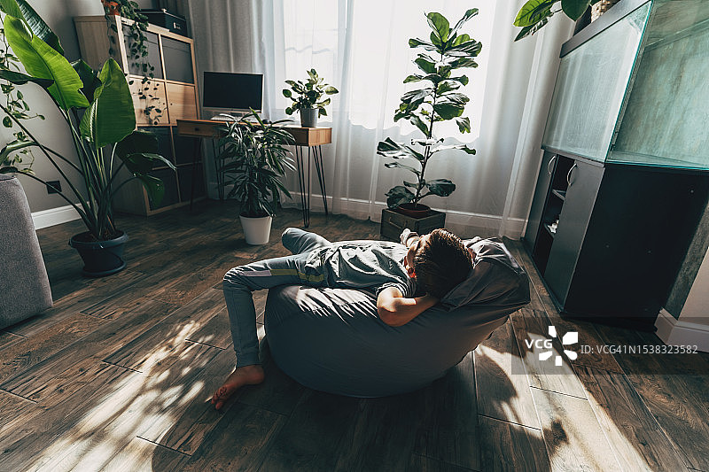 手臂骨折的男孩躺在懒人沙发上图片素材