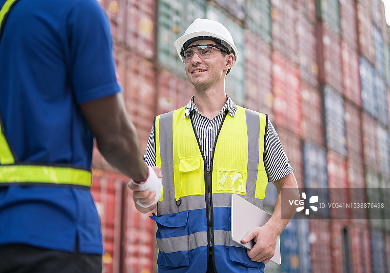 两位同事在货运集装箱旁成功达成协议并进行讨论图片素材