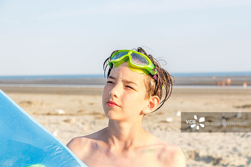 阳光明媚的日子里，在沙滩上海边眺望远方的青少年男孩肖像图片素材