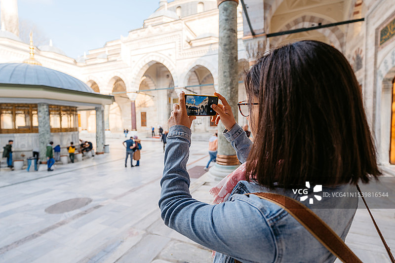 在伊斯坦布尔巴耶济德二世清真寺拍照的年轻女人图片素材