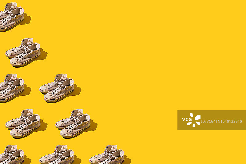 复古风磨损的白色旧篮球鞋图案，在左侧，黄色背景上。潮流、现代、复古、篮球、运动、休闲非正式鞋概念。图片素材