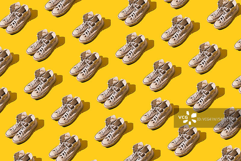 黄色背景上的复古风白色旧篮球鞋图案：潮流休闲运动概念图片素材