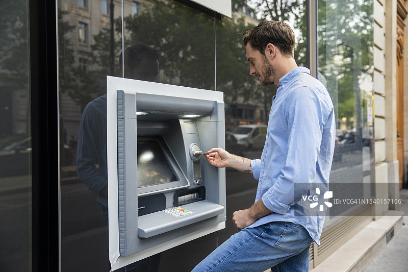 年轻男人将银行卡插入ATM机图片素材