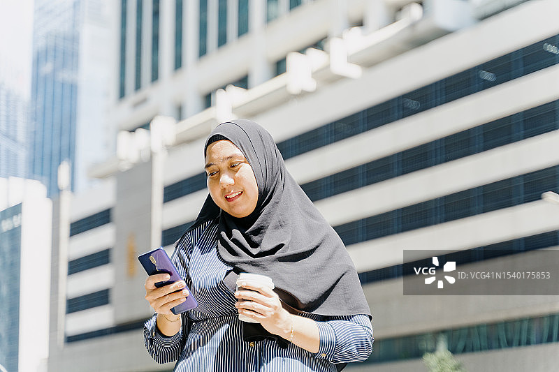 手拿咖啡杯看手机的亚洲女商人图片素材