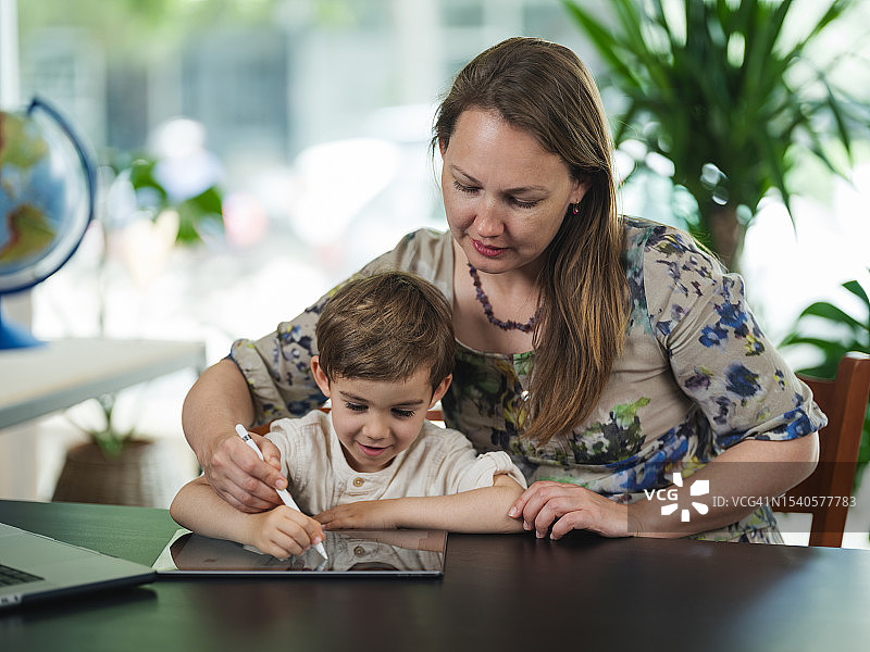母亲和儿子在平板电脑上绘画图片素材