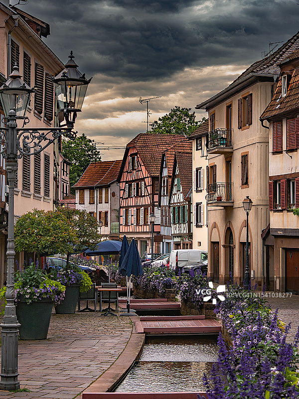 法国阿尔萨斯巴尔镇的彩色木结构房屋和溪流交汇的鹅卵石街道图片素材