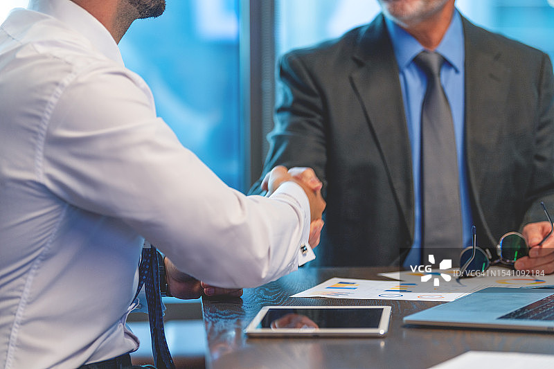两位使用科技的商人会面，一人携带笔记本电脑图片素材