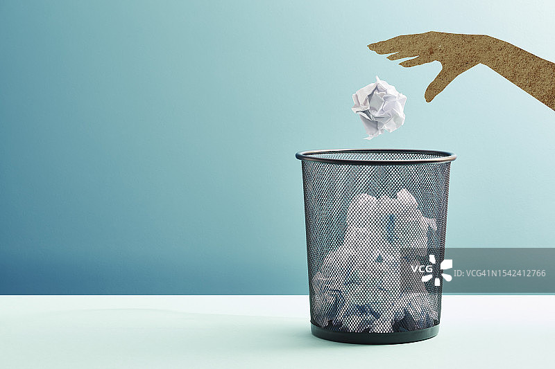 手将纸团扔进废纸篓图片素材