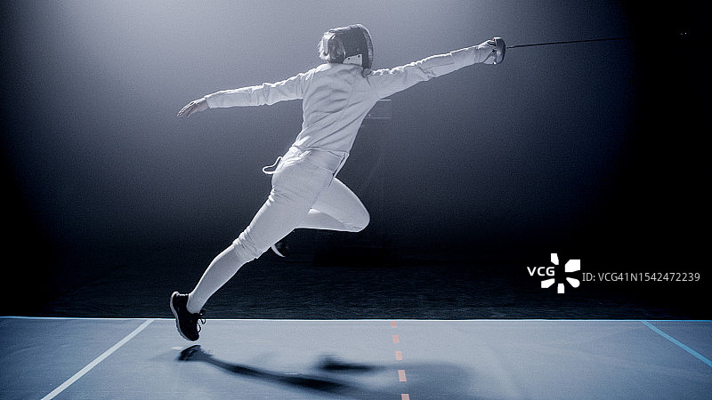 史诗级灯光下的击剑手跳跃和弓步练习图片素材