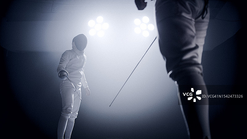 两位专业击剑手在史诗般的蓝色舞台灯光和烟雾效果中进行剑术对决（低角度）图片素材