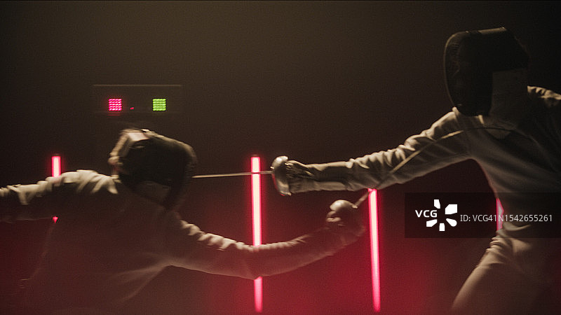 两位专业击剑手在史诗般的红色舞台灯光下进行格斗图片素材