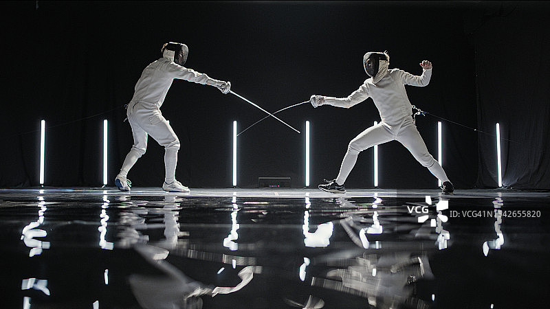 两位职业击剑手在史诗般的舞台灯光下进行花剑决斗图片素材