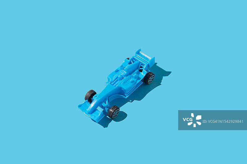 蓝色玩具一级方程式赛车，硬阴影，蓝色背景，玩具赛车极简主义运输概念图片素材