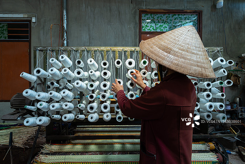 女人在织机上放置线团，用于编织莎草垫图片素材