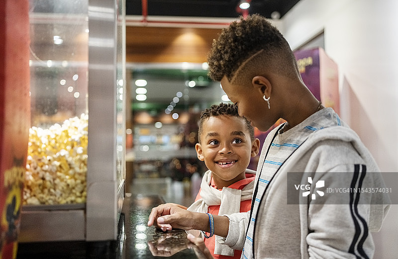 快乐的男孩们决定在电影院的 concession stand 购买商品图片素材