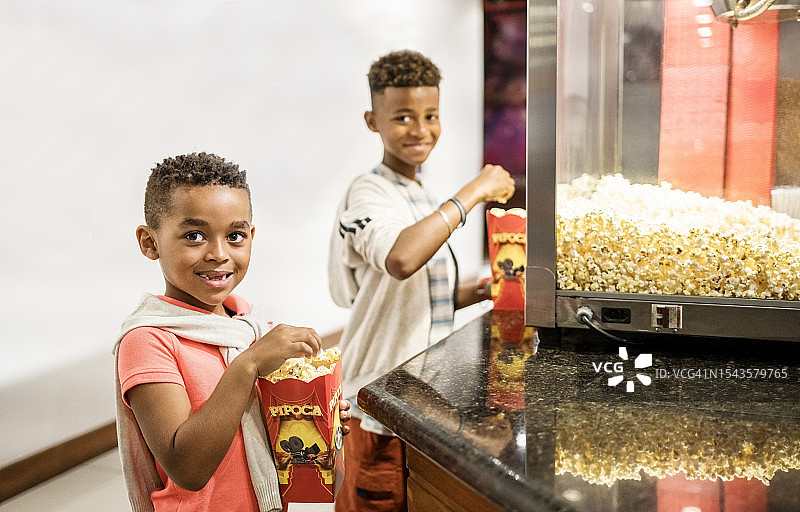 两个男孩在电影院小吃摊吃爆米花图片素材