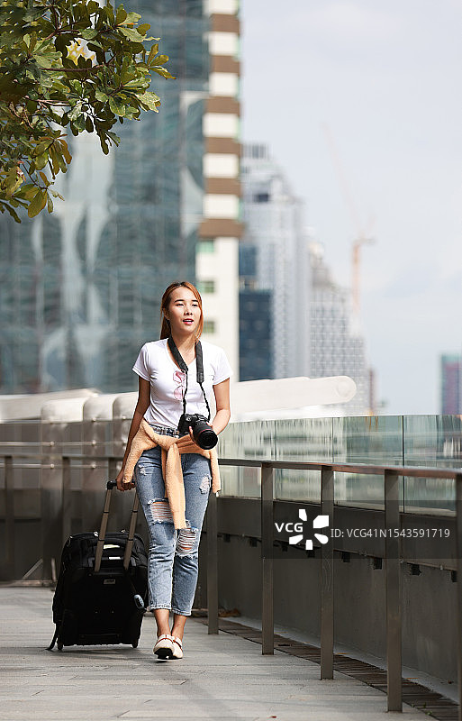 女摄影师拖着行李箱走进城市的天桥图片素材