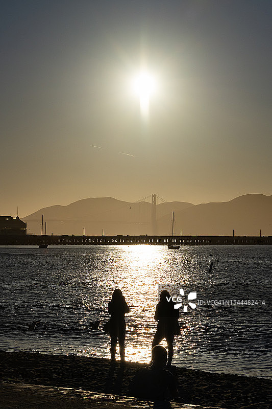 夏季傍晚旧金山海德街码头的游客剪影，背景是金门大桥图片素材