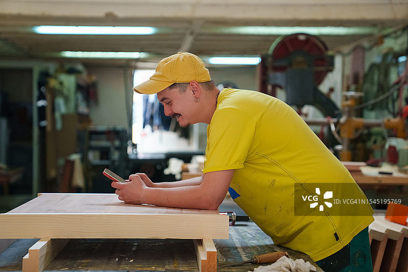 在木工作坊使用手机的男人图片素材