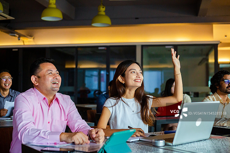 年轻女商人举手在商务会议上提问图片素材