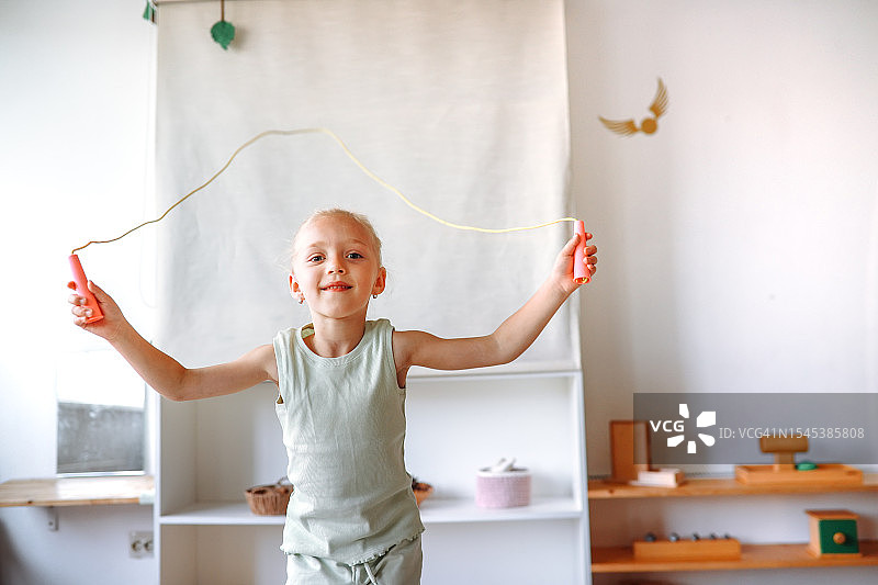 充满活力的幼儿园运动室内，金发女孩跳绳的动感瞬间：敏捷与快乐，促进儿童运动发展和训练图片素材