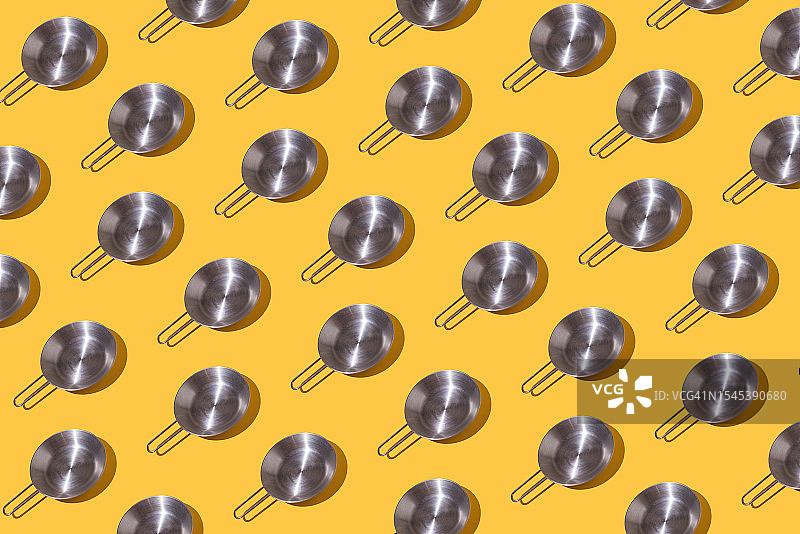 黄色背景上的钢制煎锅图案。烹饪、煎炸、烧烤、厨师、食品概念。图片素材