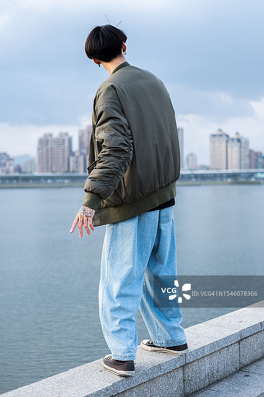 在城市河流附近摆姿势的年轻亚洲男子图片素材