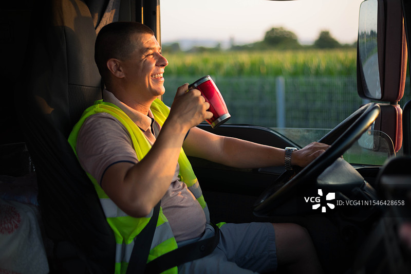 卡车司机开心驾驶并喝咖啡图片素材