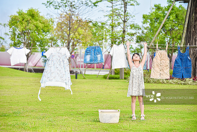 快乐的亚洲小女孩（6-7岁）在公园里晾衣服图片素材