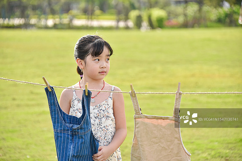 欢乐时光：在公园里晾衣服的亚洲小女孩（6-7岁），中国广东省江门市图片素材
