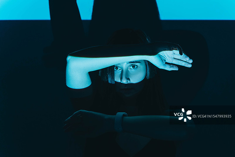 光线中用手遮挡的年轻女人，恐惧概念图片素材