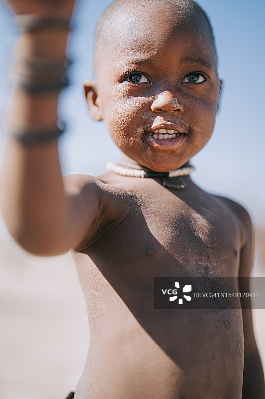 好奇的纳米比亚辛巴族男孩站在户外观看图片素材