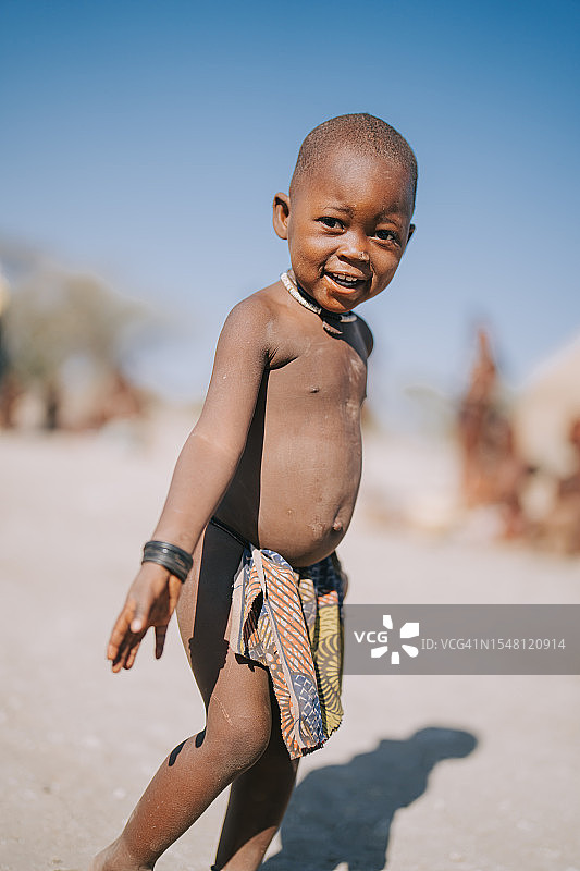 好奇的纳米比亚辛巴族男孩站在户外观看图片素材