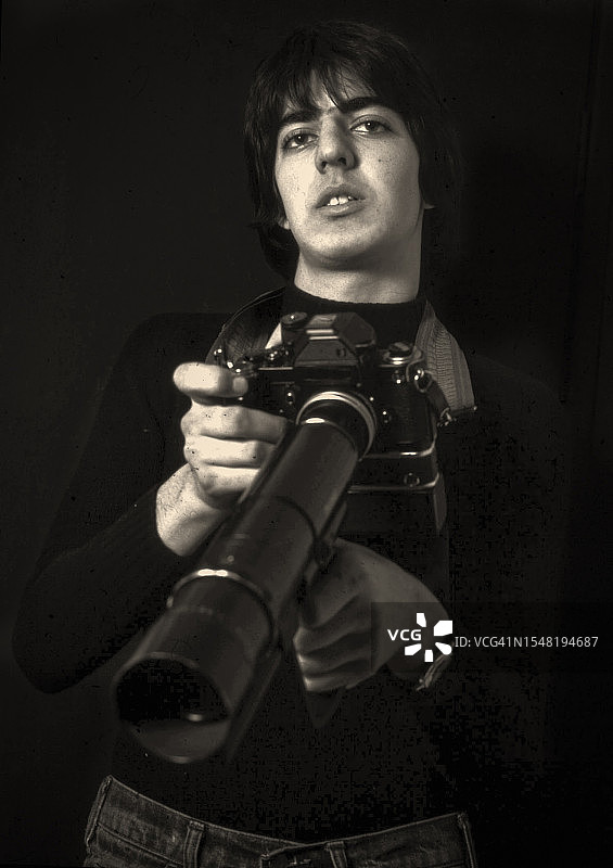 手持35mm胶片相机和400mm镜头的少年新闻摄影师图片素材