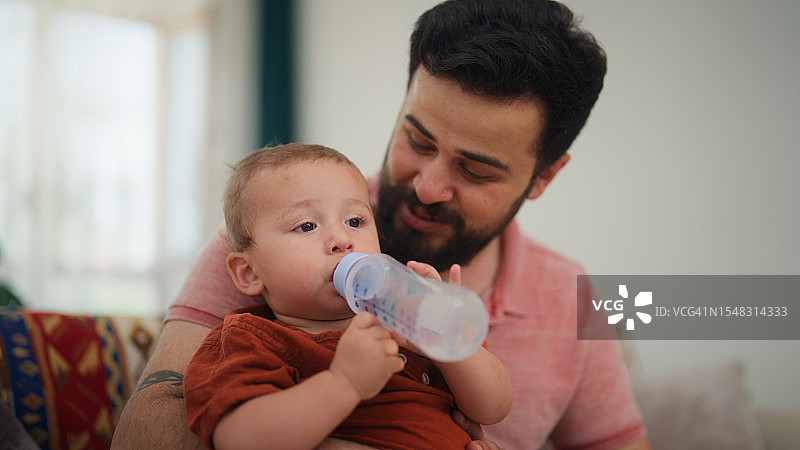 父亲在家中客厅照顾小宝宝并喂水图片素材