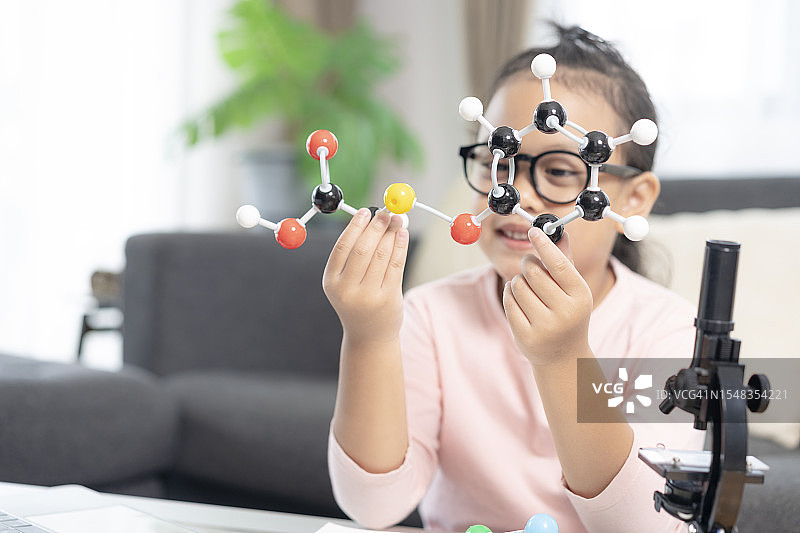女孩在家通过自学，学习分子模型实验图片素材