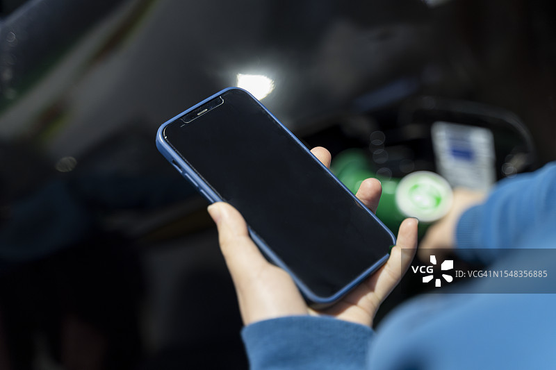 司机在加油站加油并用智能手机查看信息图片素材