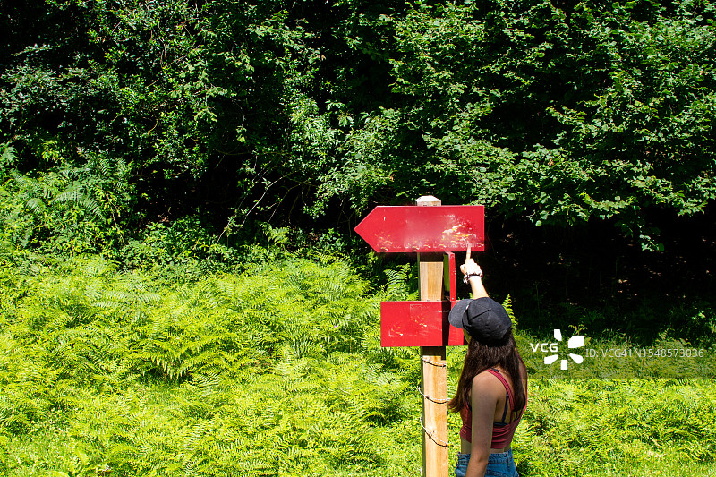 年轻女子看着山路指示牌图片素材