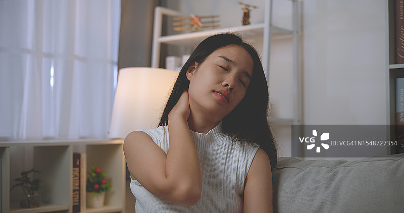年轻亚洲女子长时间工作后感到颈部疼痛图片素材