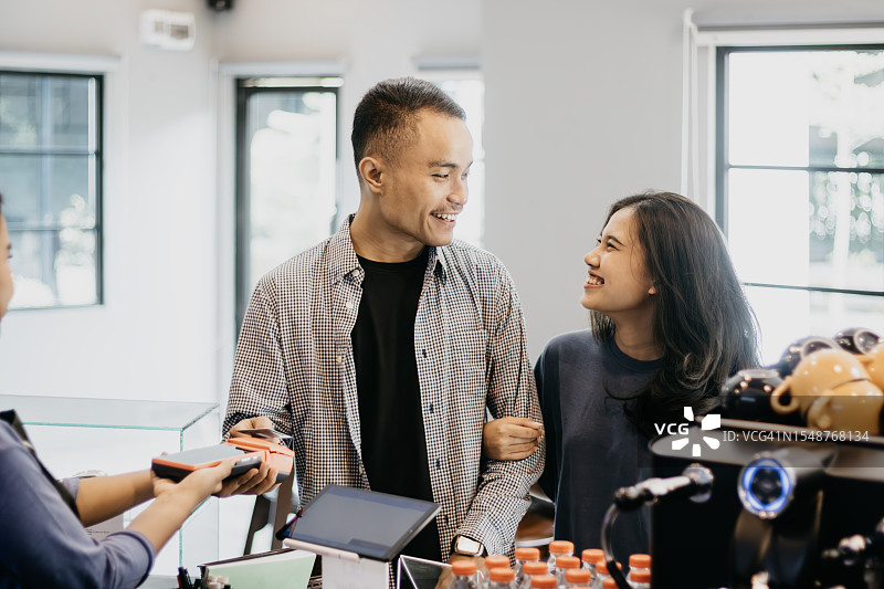 情侣在收银台使用非接触式银行卡付款图片素材