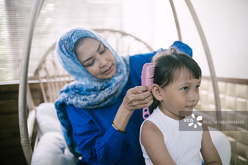 亚洲祖母在卧室里给孙女梳头图片素材