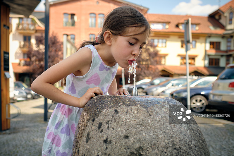 户外饮水台喝水的小女孩图片素材