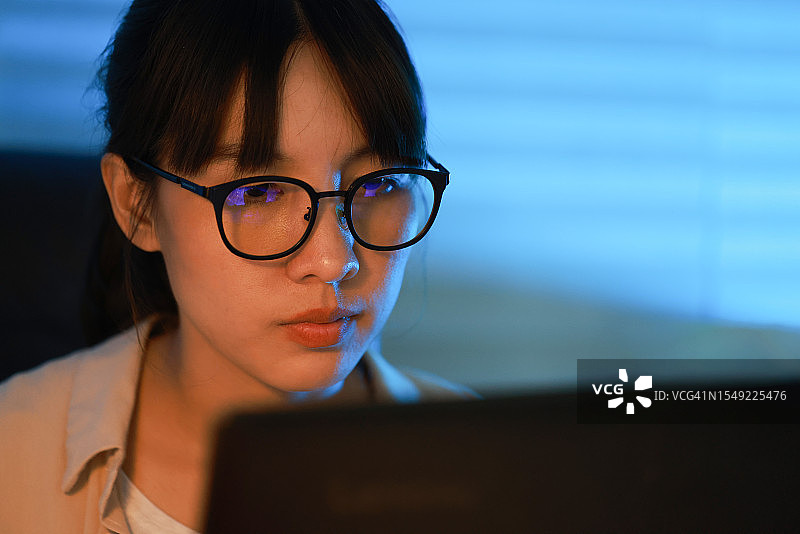 戴眼镜的年轻漂亮女人使用笔记本电脑工作面部特写图片素材