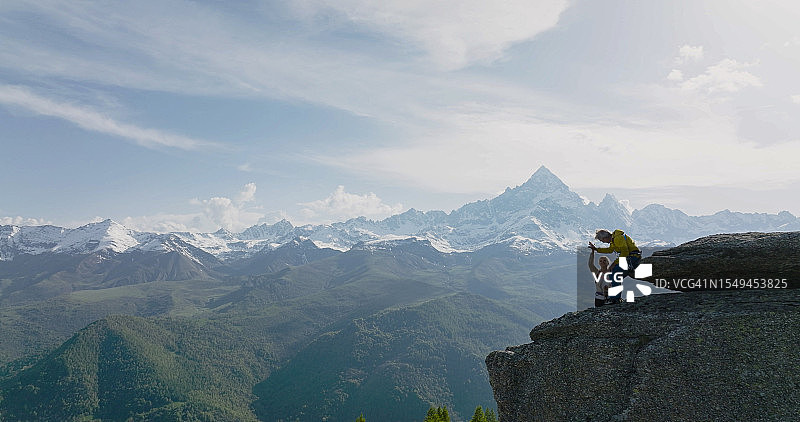老年夫妇攀登巨石航拍图片素材